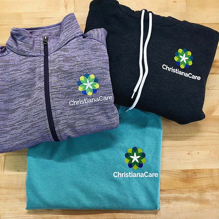 ChristianaCare staff wear: a purple quarter-zip, a charcoal hoodie and a teal T-shirt