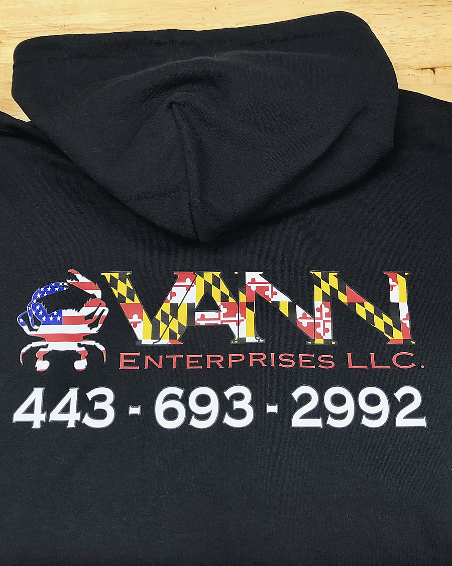 The back of a black hoodie with the VANN Enterprises logo in Maryland flag colours beside a crab in the American flag